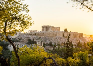 Beautiful Acropolis perched above the city, framed by the green of trees.
