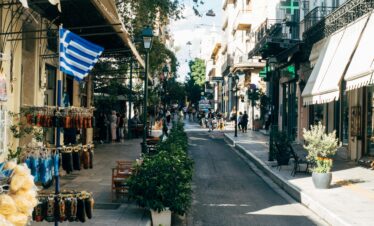 A beautiful Athens street with trees and vendors lining each side.
