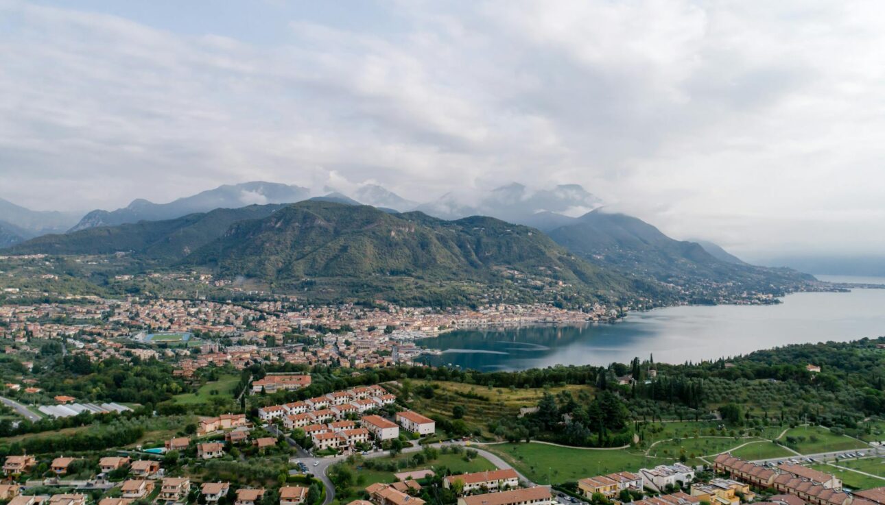 Aerial shot of town beside Lake Garda with mountains in the background