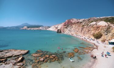 Firiplaka beach stretches far with the red cliffs towering over the beach.